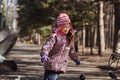 Girl in a red jacket, hat and glasses chasing pigeons in the park Royalty Free Stock Photo