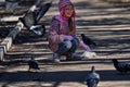 Girl in a red jacket, hat and glasses chasing pigeons in the park. Royalty Free Stock Photo