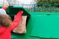 Girl in a red jacket, throws a paper bag in a dumpster, rear view Royalty Free Stock Photo