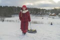 A girl in a red jacket walks down a snow-covered slide with tubing Royalty Free Stock Photo