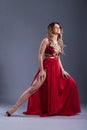 Girl in a red long dress in the studio, on a gray background.