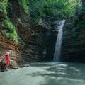 Girl in red looks at the waterfall Maiden spit on the stream Rufabgo, Adygea, Russia Royalty Free Stock Photo