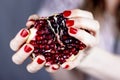 Girl with red manicure holds a pomegranate. Juicy and tasty pomegranate Royalty Free Stock Photo