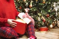 A girl in red pajamas sits under a Christmas tree and opens a gift. Royalty Free Stock Photo