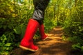 A girl in red rubber boots is walking along a forest path