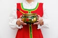 A girl in a red Russian folk dress holds Khokhloma bowl and spoon, isolated on white