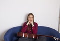 A girl in a red shirt sitting on a double chair.