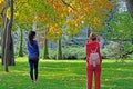 A girl in a red suit takes pictures of a model in a city park.