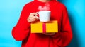 Girl in red sweater with gift box and cup of coffee Royalty Free Stock Photo