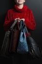 Girl in a red sweater holds leather handbags of different colors, women in a red sweater holds leather bags of different kinds, fo Royalty Free Stock Photo