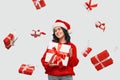 Girl in a red sweater and Santa Claus hat holding white giftbox with red ribbon Royalty Free Stock Photo