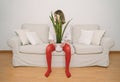 Girl in red tights and white t-shirt sitting on sofa holding plant between her legs