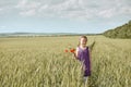 Girl with red tulip flowers posing in the wheat field, bright sun, beautiful summer landscape Royalty Free Stock Photo