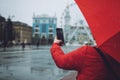 Girl with red umbrella taking photos in the rain. Woman traveler take pictures on rainy day Royalty Free Stock Photo