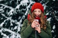 Girl in red winter hat and scarf using smartphone and smiling. Royalty Free Stock Photo