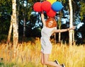 Girl redhead jumping with ballons at the yellow spikelets