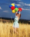 Girl redhead jumping with ballons at the yellow spikelets and blue sky Royalty Free Stock Photo