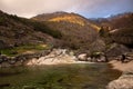 Girl reflecting by the river beach with the mountain in the background. Loriga river beach with Serra da Estrela in background