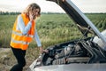 Girl in reflecting vest with phone, broken car Royalty Free Stock Photo