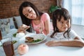 Girl refuses to eat when her older sister feeds her food with a spoon Royalty Free Stock Photo