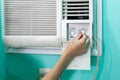 The girl regulates the temperature of a small room air conditioner. Royalty Free Stock Photo