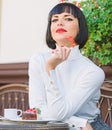 Girl relax cafe with cake dessert. Woman attractive elegant brunette eat gourmet cake cafe terrace background. Gourmet Royalty Free Stock Photo