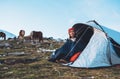 Girl relax in campsite, tourist in camp tent on mountain nature, hiker woman enjoys wild horses on valley camping trip Royalty Free Stock Photo