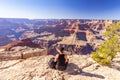 The girl relaxes on the edge of a rock overlooking the Grand Canyon in the USA and admires the view