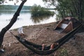 Girl relaxes in a hammock. Quickly folding tent and campfire. River bank. Wild camping. Travel equipment. Vacation and travel Royalty Free Stock Photo