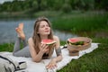 Girl relaxing and eat watermelon outdoor near lake. Picnic in nature