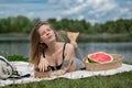 Girl relaxing and eat watermelon outdoor near lake. Picnic in nature