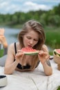 Girl relaxing and eat watermelon outdoor near lake. Picnic in nature