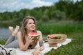 Girl relaxing and eat watermelon outdoor near lake. Picnic in nature