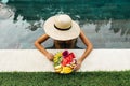 Girl relaxing and eating fruit plate by the hotel pool. Exotic summer diet.