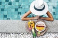 Girl eating exotic fruits in the pool