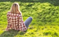 Girl is relaxing on meadow. Blonde beautiful young woman is sitting on the grass and enjoying the sun. Outdoor. Sunny day. Wearing Royalty Free Stock Photo