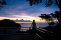 The girl, relying on the railing, looks at the sunset with beautiful clouds from the viewing platform on the island of Phi Phi.