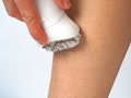 The girl removes the hair from her leg with an electric epilator.