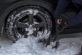 The girl removes snow from the rear wheel of her car,