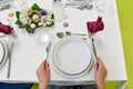 A girl in a restaurant sits at a table with empty plates and orders food Royalty Free Stock Photo