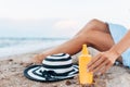 Girl resting on the beach, beautiful tanned legs against the blue sea, jar of cream Royalty Free Stock Photo