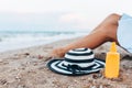 Girl resting on the beach, beautiful tanned legs against the blue sea, jar of cream Royalty Free Stock Photo