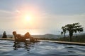 The girl is resting on the edge of the infinity pool. overlooking the tropical jungle and the beach. Near two coconuts with Royalty Free Stock Photo