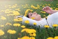 Girl resting on a sunny day in meadow of yellow dandelions Royalty Free Stock Photo