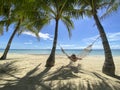 Girl resting and swinging on hammock in paradise resort.Beautiful sandy white beach with a turquoise sea in grove with palm trees