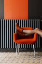 The girl rests her legs on a chair. Orange boots, a chair and part of the wall in a black conference room at the hotel. Relaxation Royalty Free Stock Photo