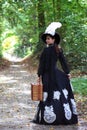 Girl in retro dress 18th century with valise in park Royalty Free Stock Photo