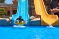 Girl ride on a water park slides with and use smartphone