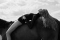 Girl rider lies bent on a horse in the field. Fashion portrait of a woman and the mares are horses in the village in the sky Royalty Free Stock Photo