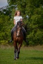 A girl rider trains riding a horse on a spring day